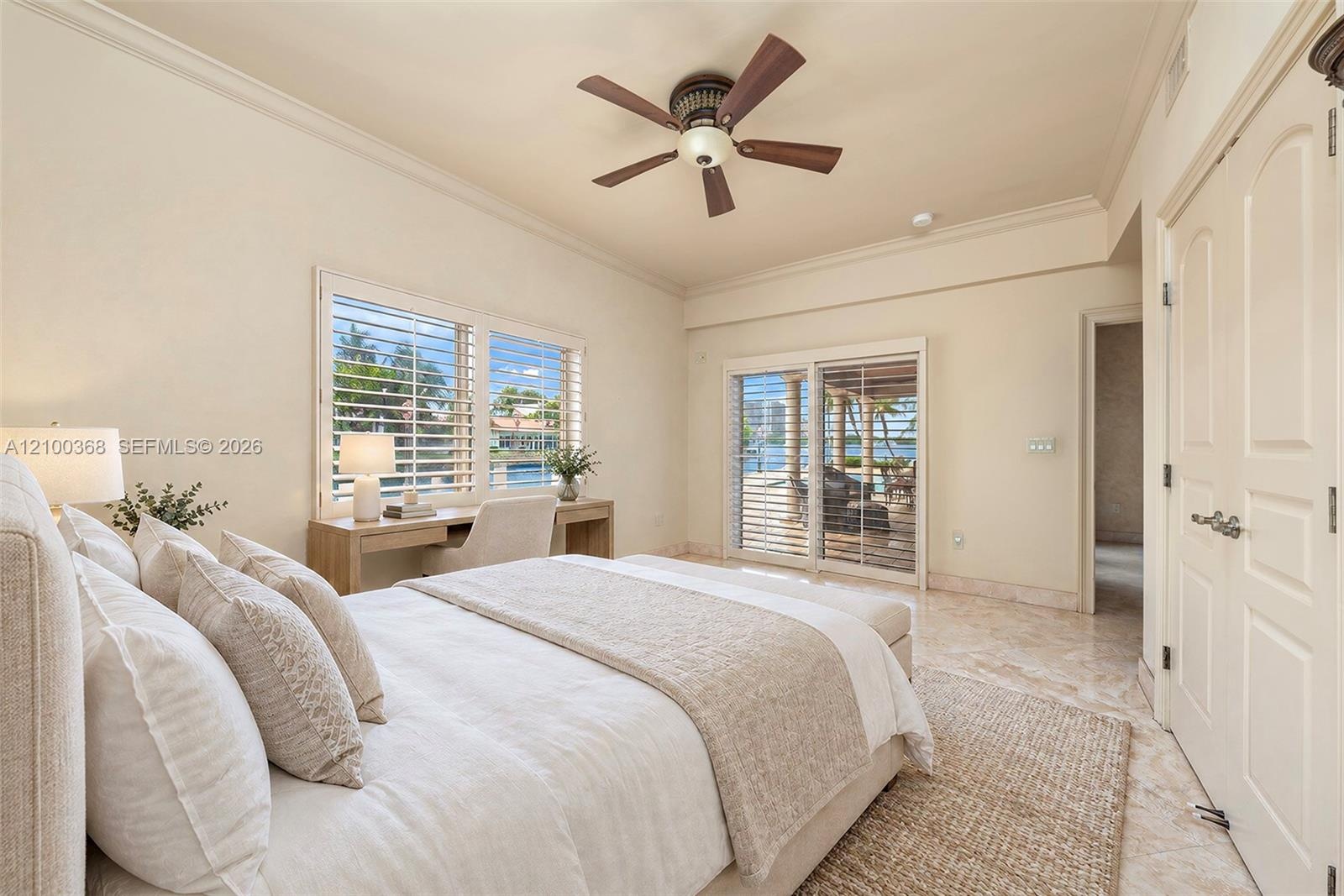 Room featuring stone-finish tile flooring, ceiling fan, crown molding, built-in desk, and sliding glass doors