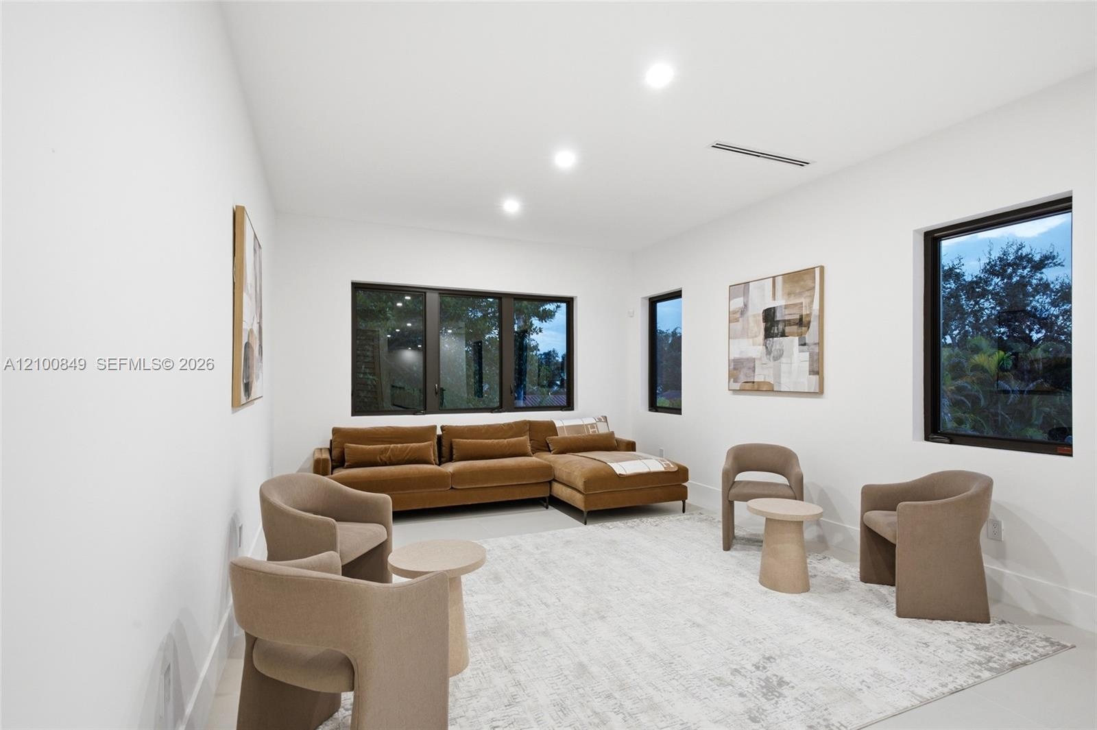 Bright interior space featuring recessed ceiling lighting, large-format smooth flooring, and expansive windows framed in dark metal
