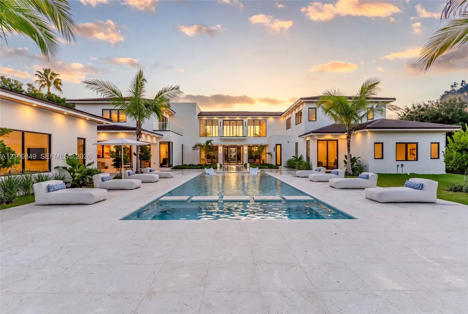 Contemporary estate exterior featuring a sprawling limestone pool deck, rectangular swimming pool with integrated stepping stones, multi-wing architec