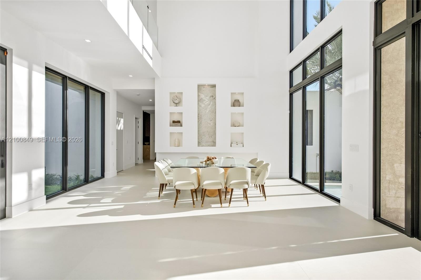 Double-height ceiling, large-format tile flooring, floor-to-ceiling black-framed windows, and built-in wall niches