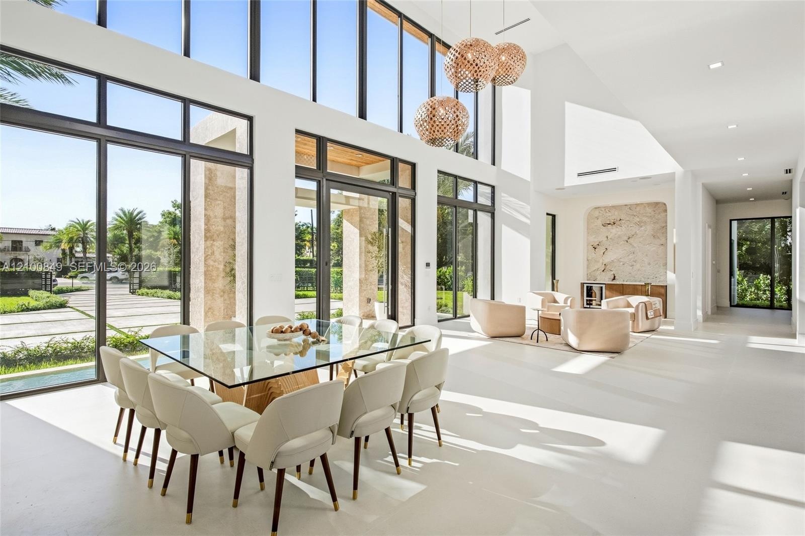Double-height vaulted ceilings featuring expansive floor-to-ceiling windows, structured stone-clad accent wall, and polished concrete flooring