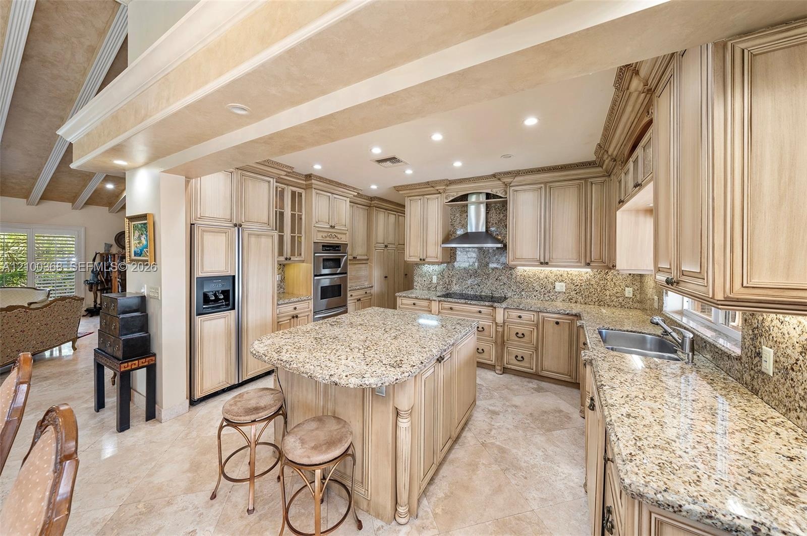 Kitchen featuring custom cabinetry with detailed millwork, stone countertops, a central island, recessed lighting, and stainless steel appliances