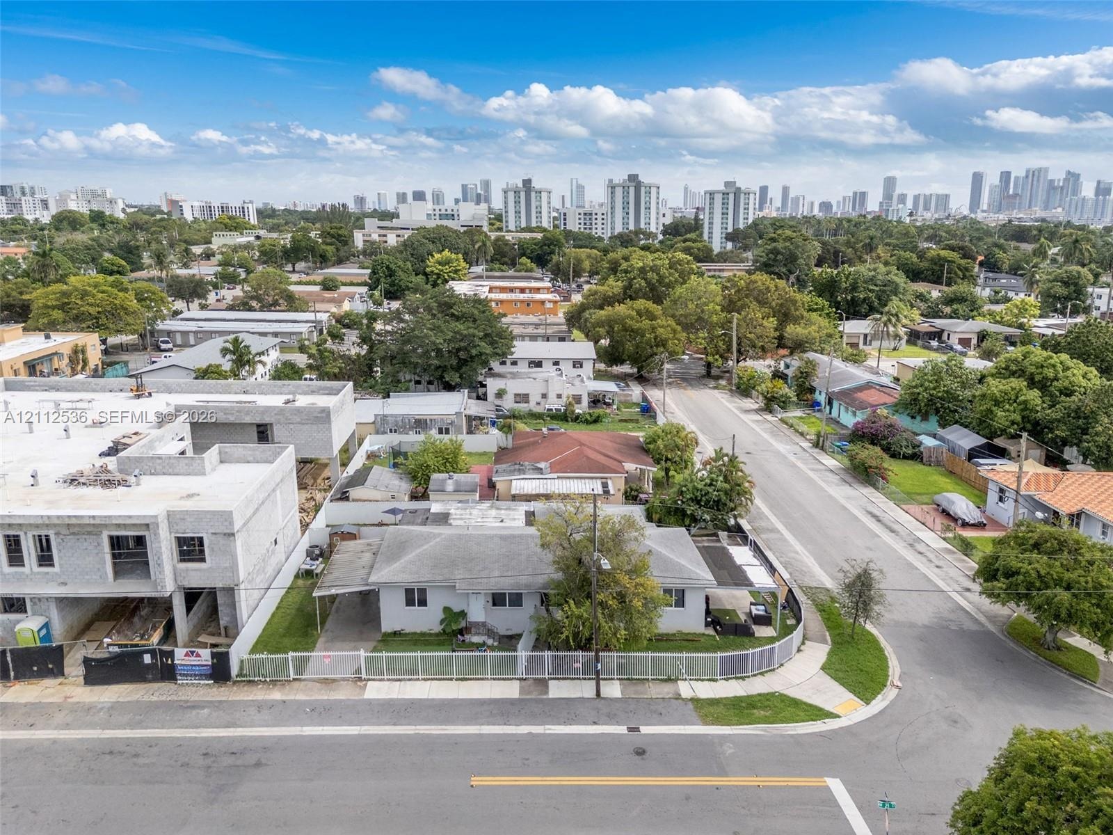 Corner lot featuring a single-story structure with a metal-framed carport, a partially fenced perimeter, and established trees