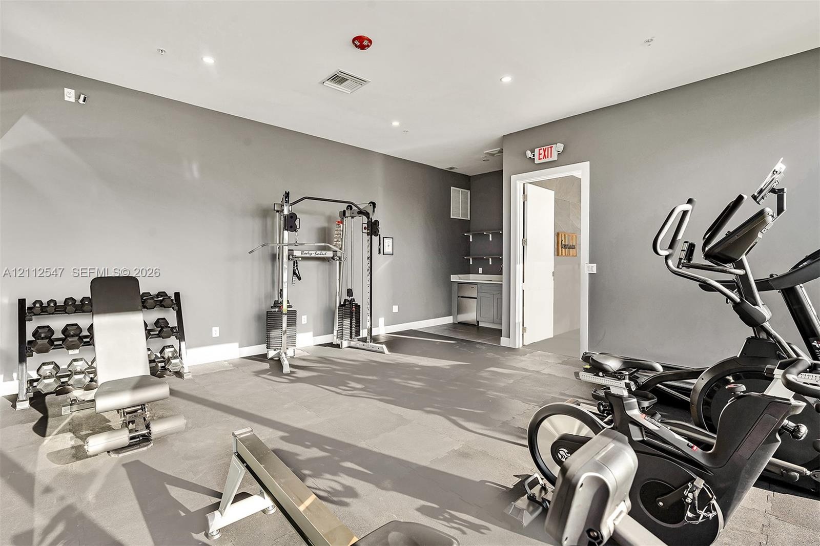Fitness room featuring rubberized flooring, recessed lighting, and a built-in cabinetry unit with a countertop