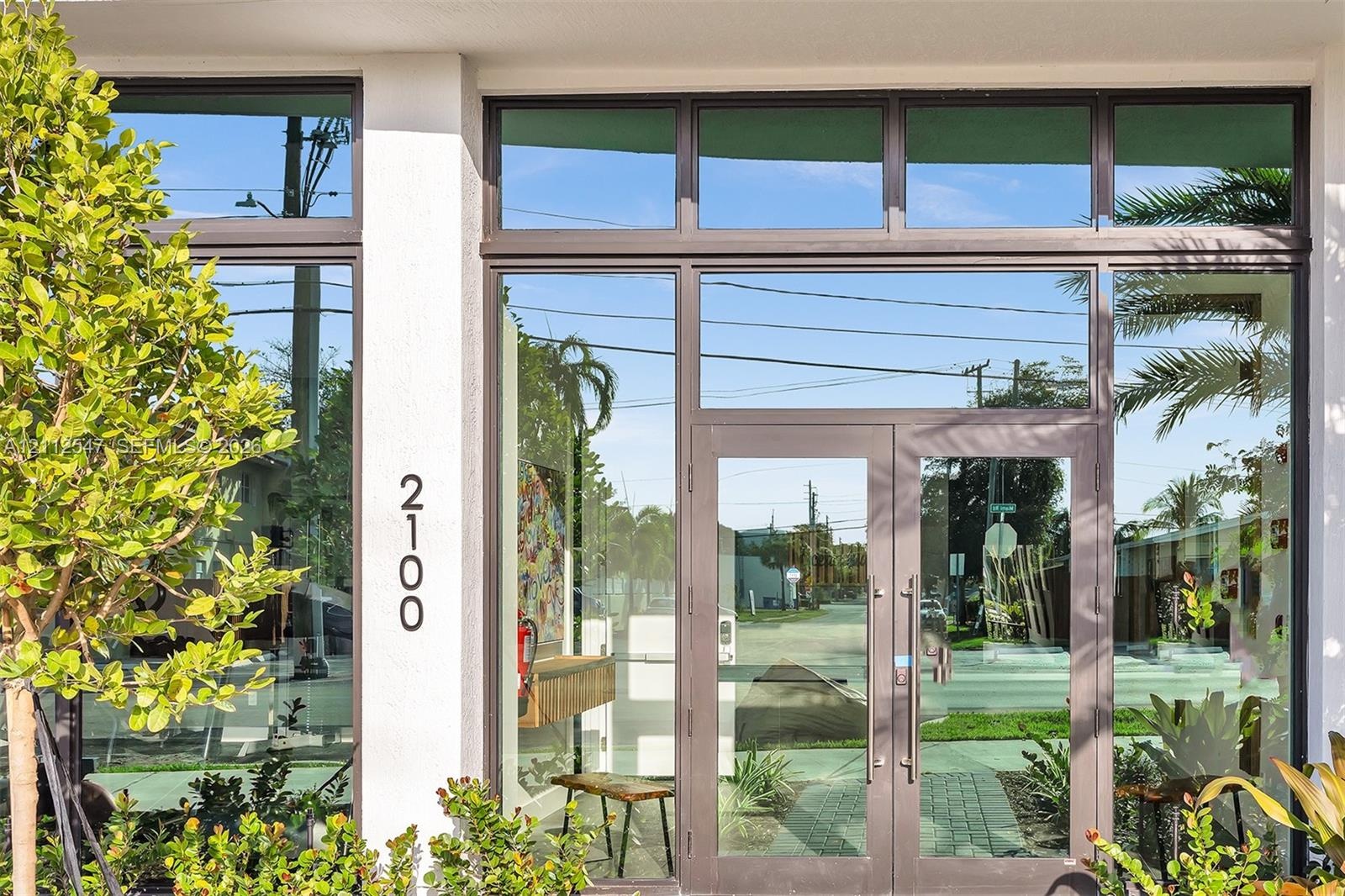 Entrance featuring a double-glass door entry, expansive floor-to-ceiling windows, dark-finished metal framing, and clerestory window accents