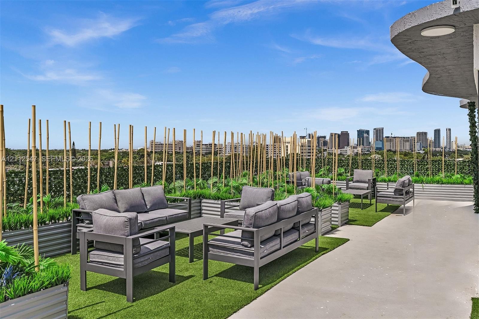 Rooftop terrace featuring concrete flooring, integrated corrugated metal planters, bamboo privacy screens, and artificial turf