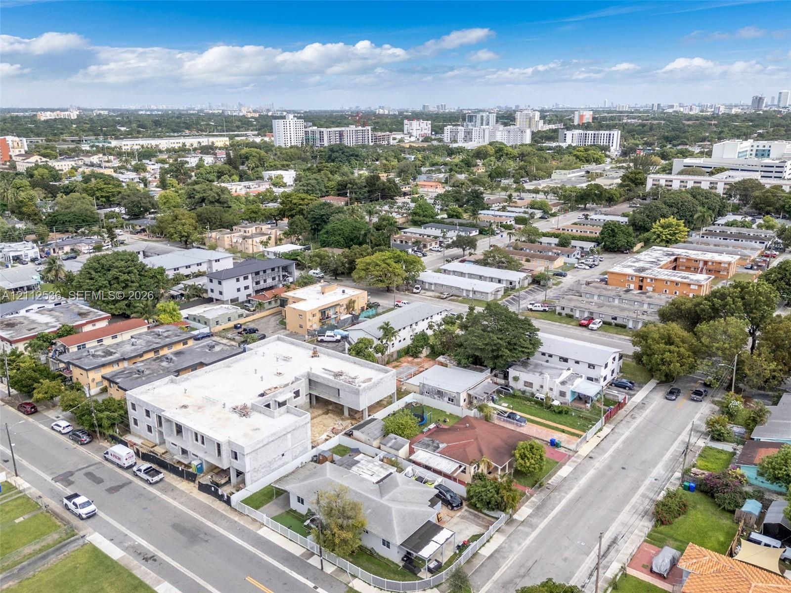 Aerial perspective of a multi-level concrete residential structure under construction featuring an open-concept building footprint and urban surroundi