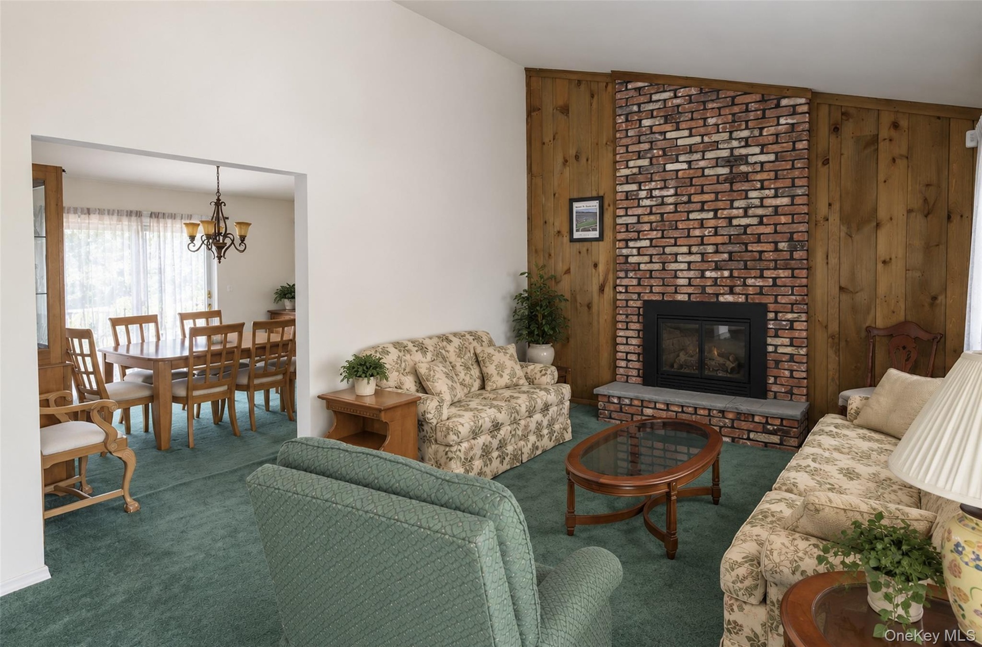 Vaulted ceilings, floor-to-ceiling brick fireplace with stone hearth, and natural wood-paneled accent wall
