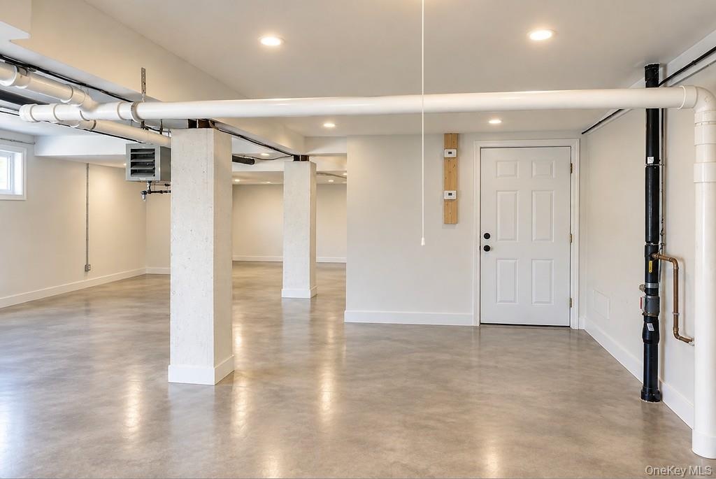 Open-concept interior space  concrete flooring, recessed lighting, and structural support columns