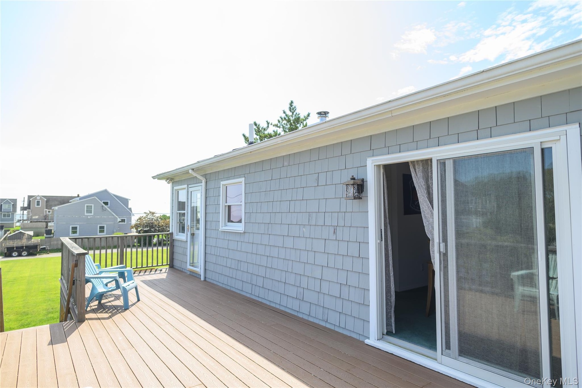 Exterior featuring gray shingle siding, a composite deck, white gutters, and a sliding glass door