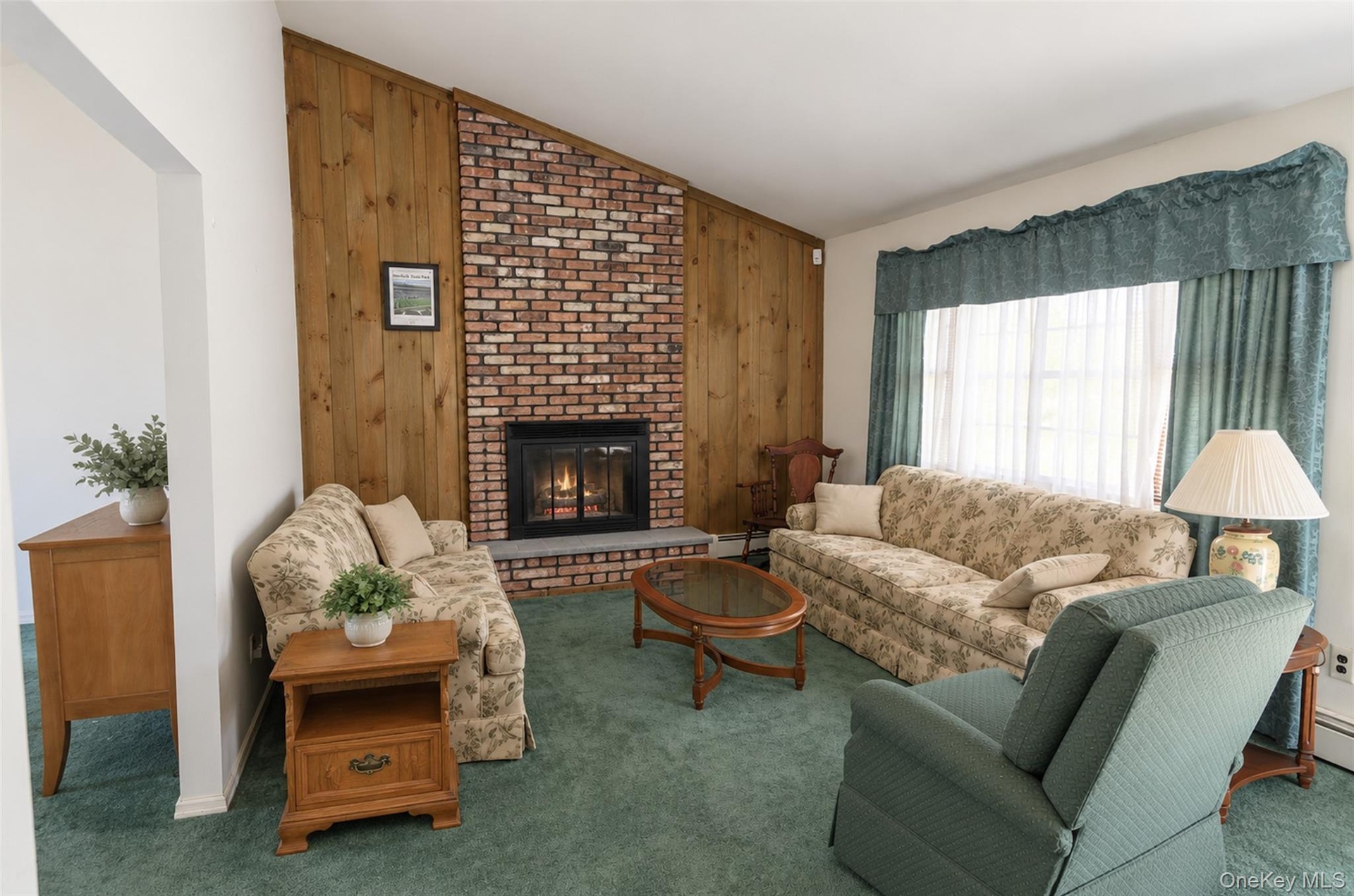 Floor-to-ceiling brick fireplace with a stone hearth, vaulted ceiling, and wood-paneled accent wall