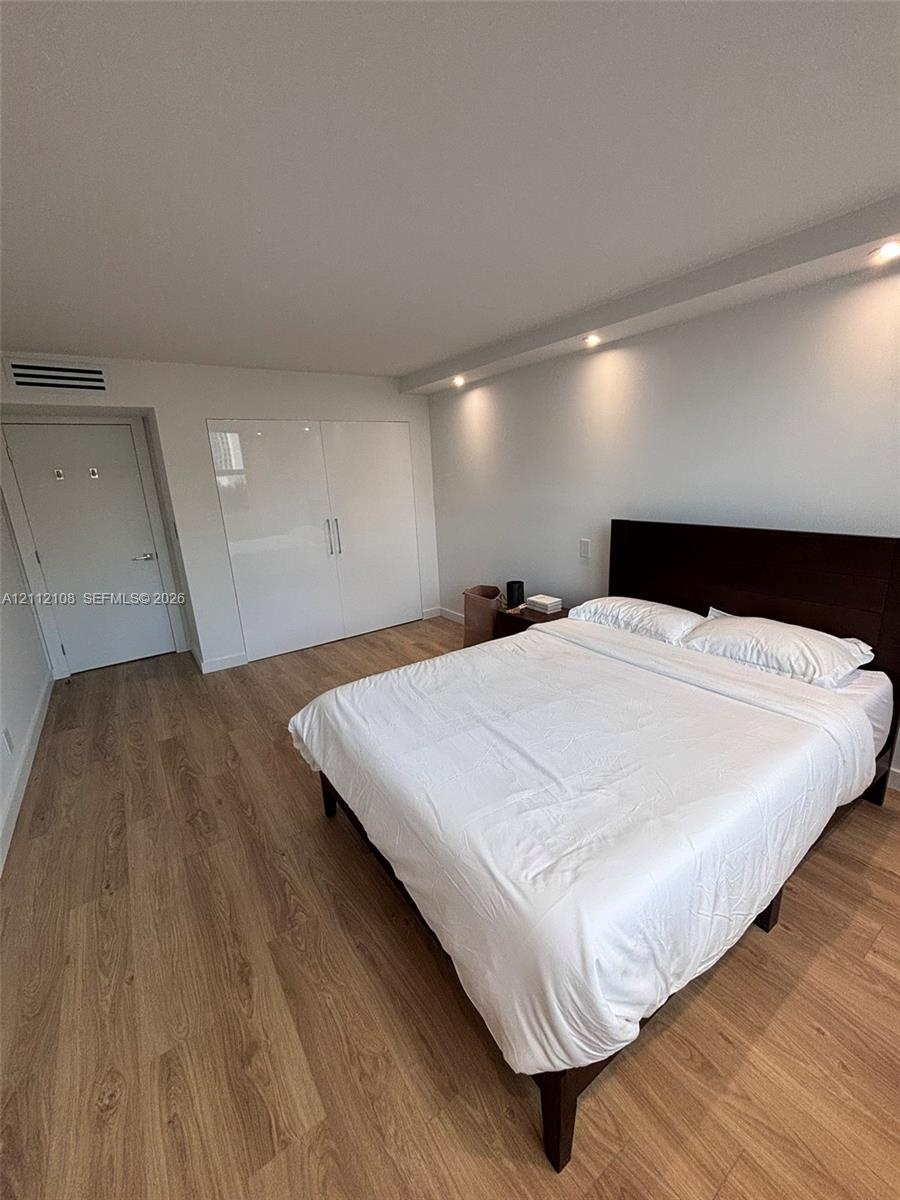 Wood-finish flooring, high-gloss built-in cabinetry, and recessed lighting in a coffered ceiling element
