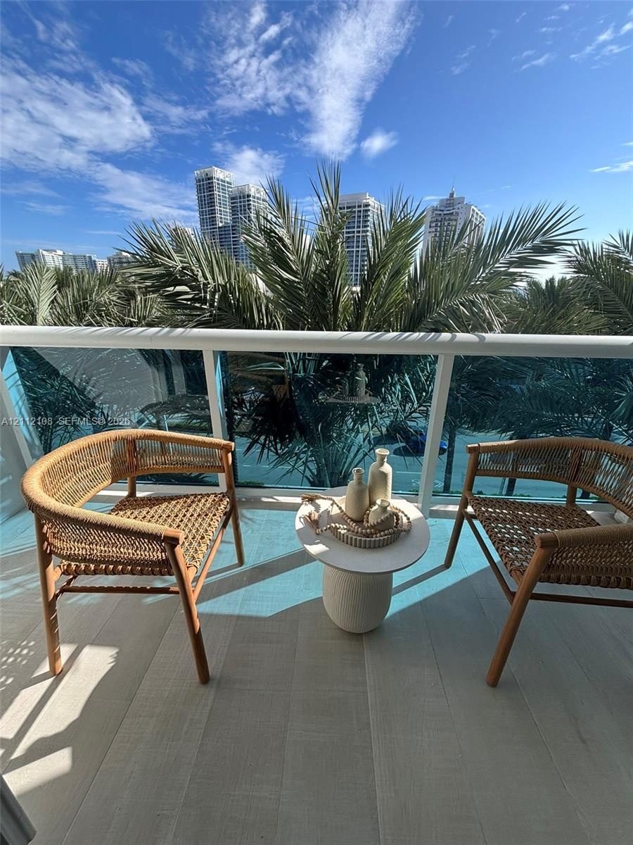 Private balcony featuring wood-finish flooring and a tempered glass railing