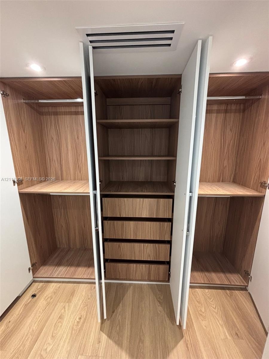 Built-in wardrobe system featuring wood-finish cabinetry, integrated shelving, four pull-out drawers, and dual hanging rods