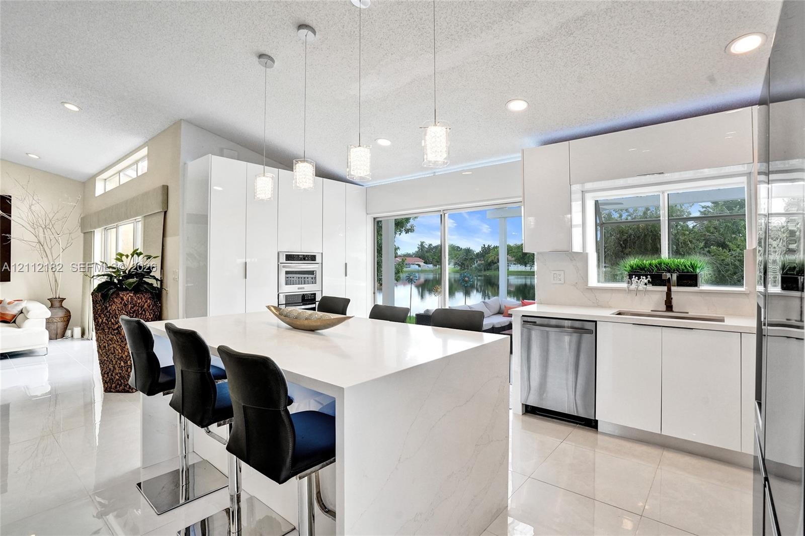 Modern kitchen featuring high-gloss cabinetry, a central island with a stone countertop, built-in stainless steel appliances, polished tile flooring, 