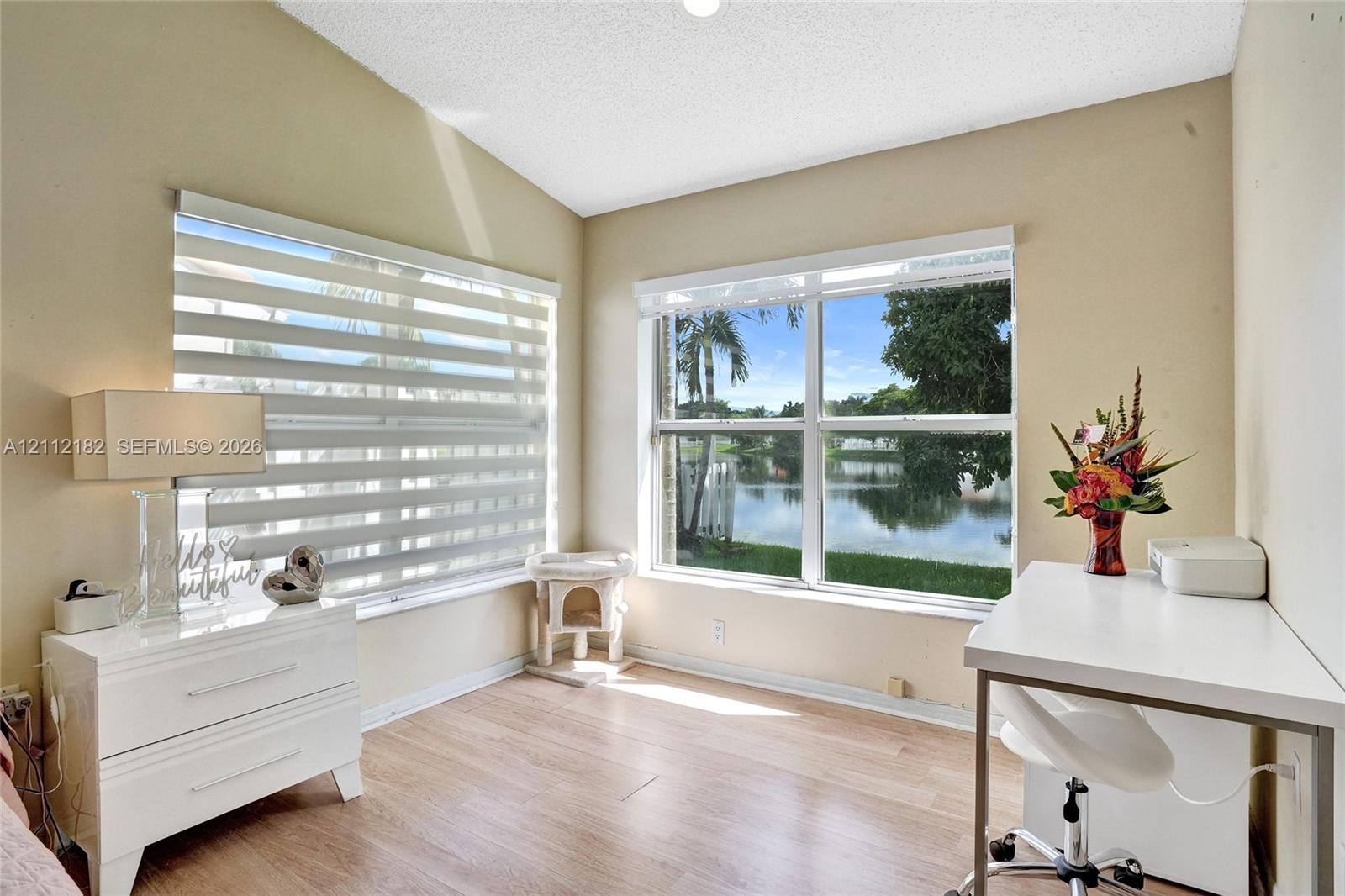 Vaulted ceiling with wood-finish flooring, dual-aspect windows, and water-facing exterior exposure