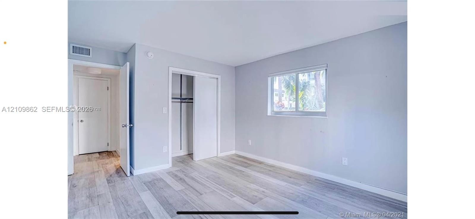 Neutral interior featuring wood-finish flooring, sliding closet doors, and a horizontal window