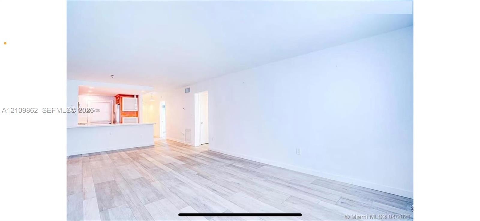 Open-concept interior featuring wood-finish flooring and a kitchen pass-through counter