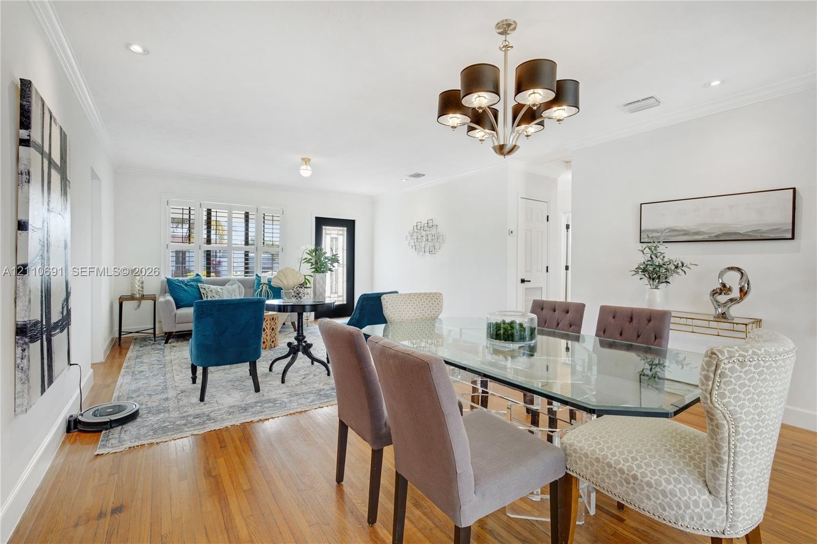 Open-concept interior featuring wood-finish flooring, multi-light chandelier, crown molding, recessed lighting, and multi-pane window with shutter acc