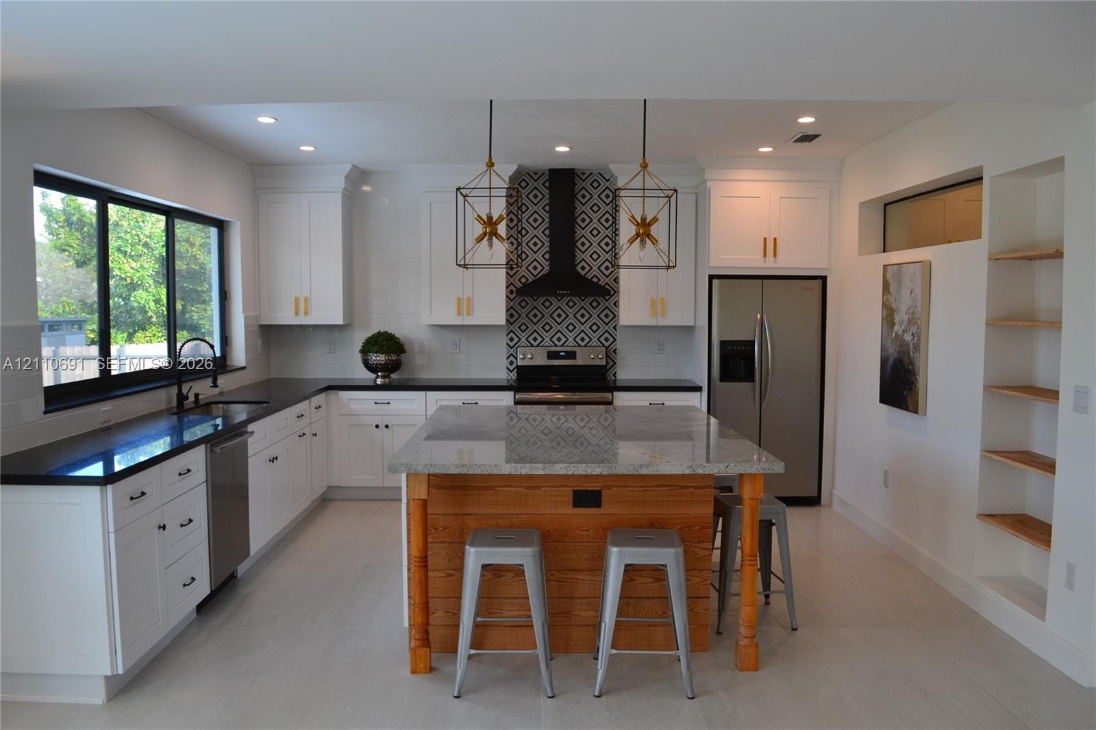 Kitchen featuring white shaker cabinetry, stone-topped central island with wood paneling, geometric tile backsplash, recessed lighting, and built-in s