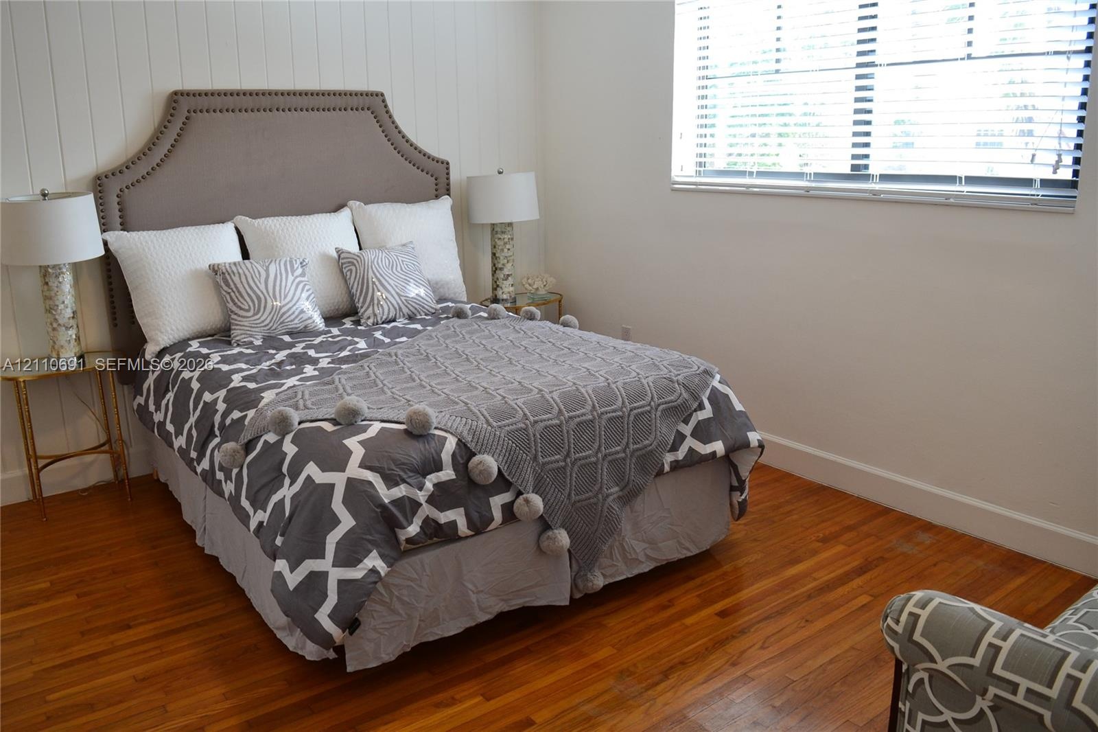 Vertical board-and-batten wall detailing, polished wood-finish flooring, and horizontal window blinds
