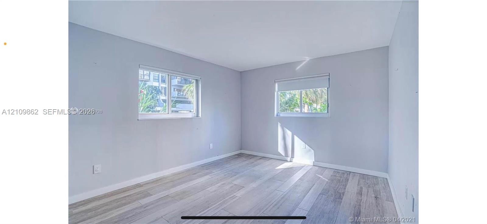 Room with neutral-toned walls, wood-finish tile flooring, and two sliding windows