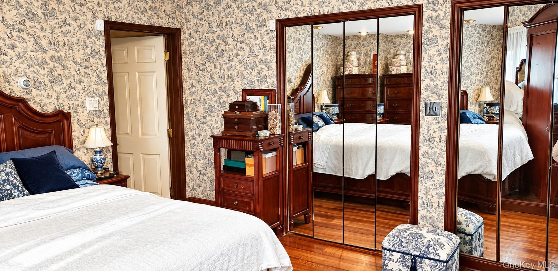 Wood-finish flooring, dual floor-to-ceiling mirrored closet doors, and wood-trim door casing