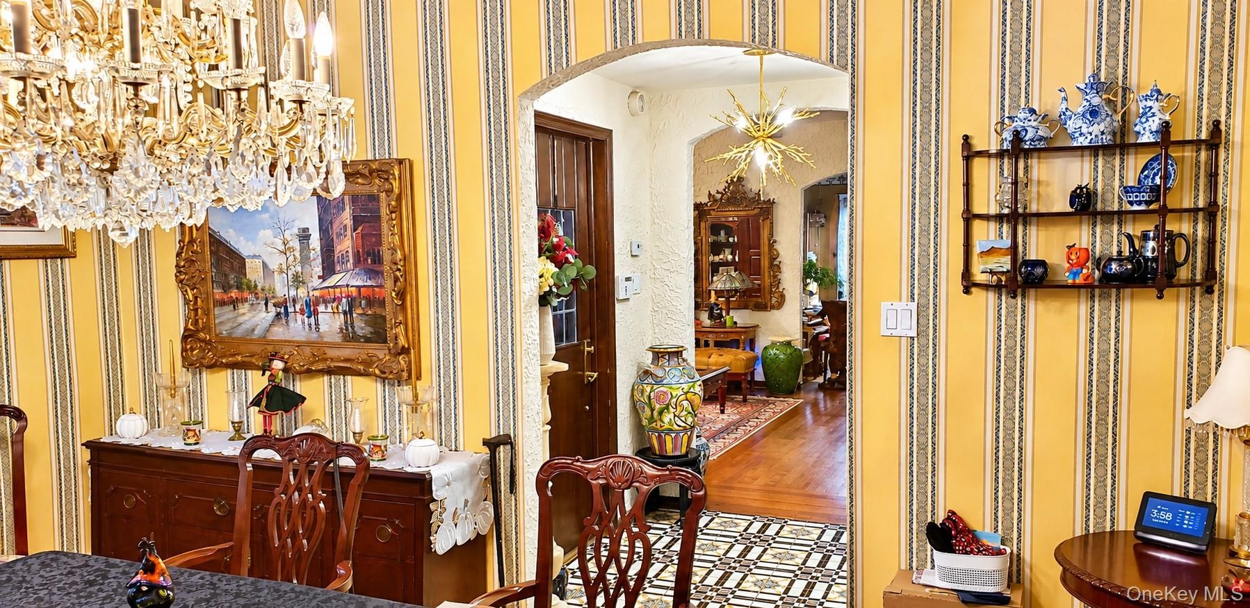 Arched entryway featuring a multi-tiered crystal chandelier, striped wallpaper, built-in shelving, and patterned tile flooring