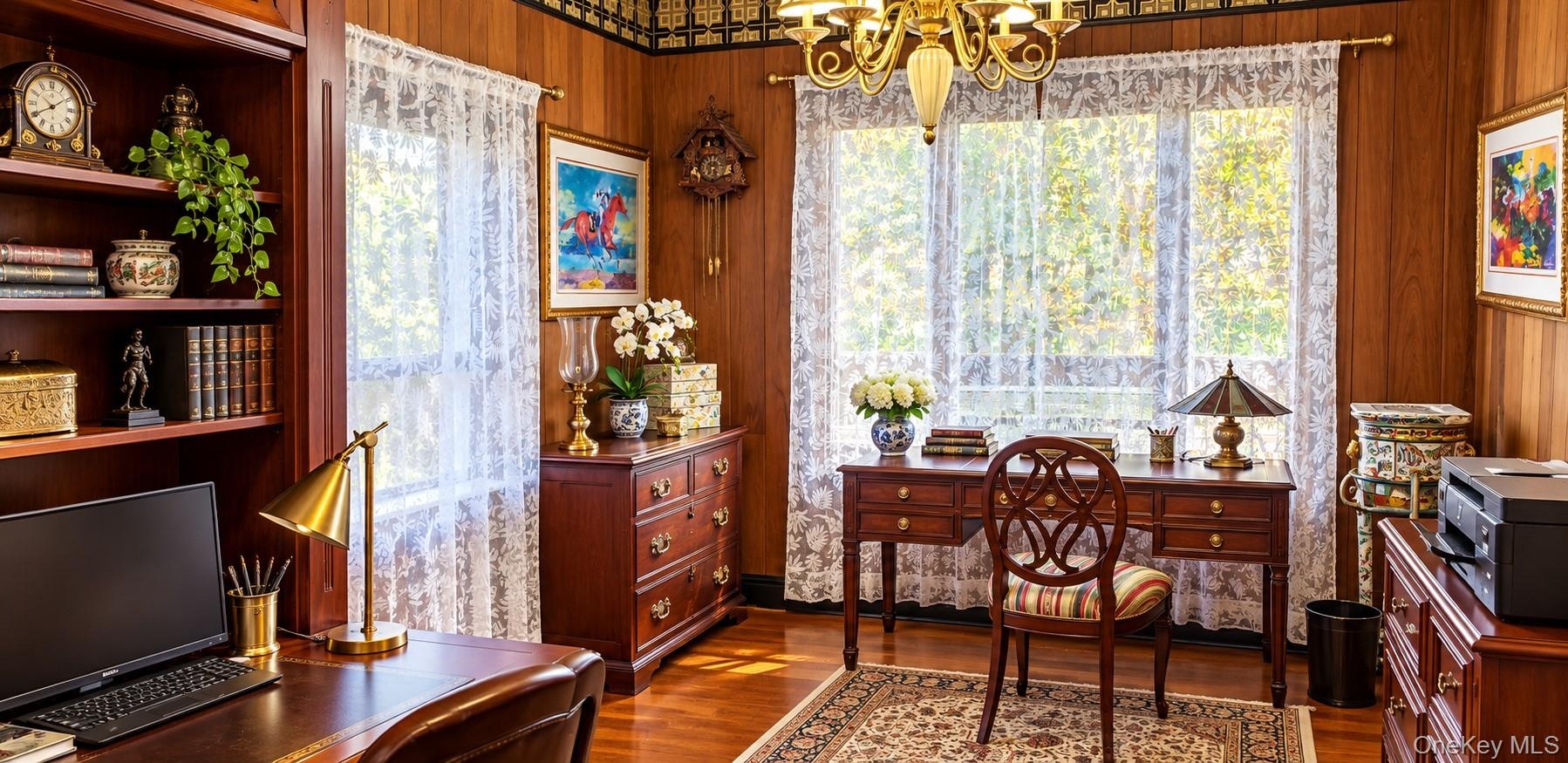 Wood-paneled walls with decorative crown molding, floor-to-ceiling built-in shelving, hardwood flooring, and a multi-arm chandelier