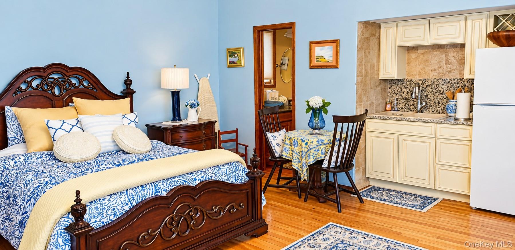 Wood-finish flooring, kitchenette featuring shaker-style cabinetry, stone-style tile backsplash, and light-toned countertop