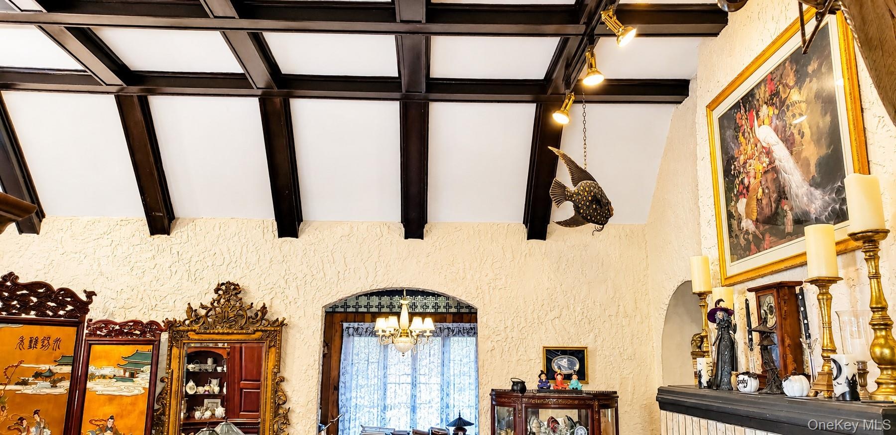 Vaulted ceiling featuring dark-finished exposed beams, textured wall finish, and archway architectural detailing