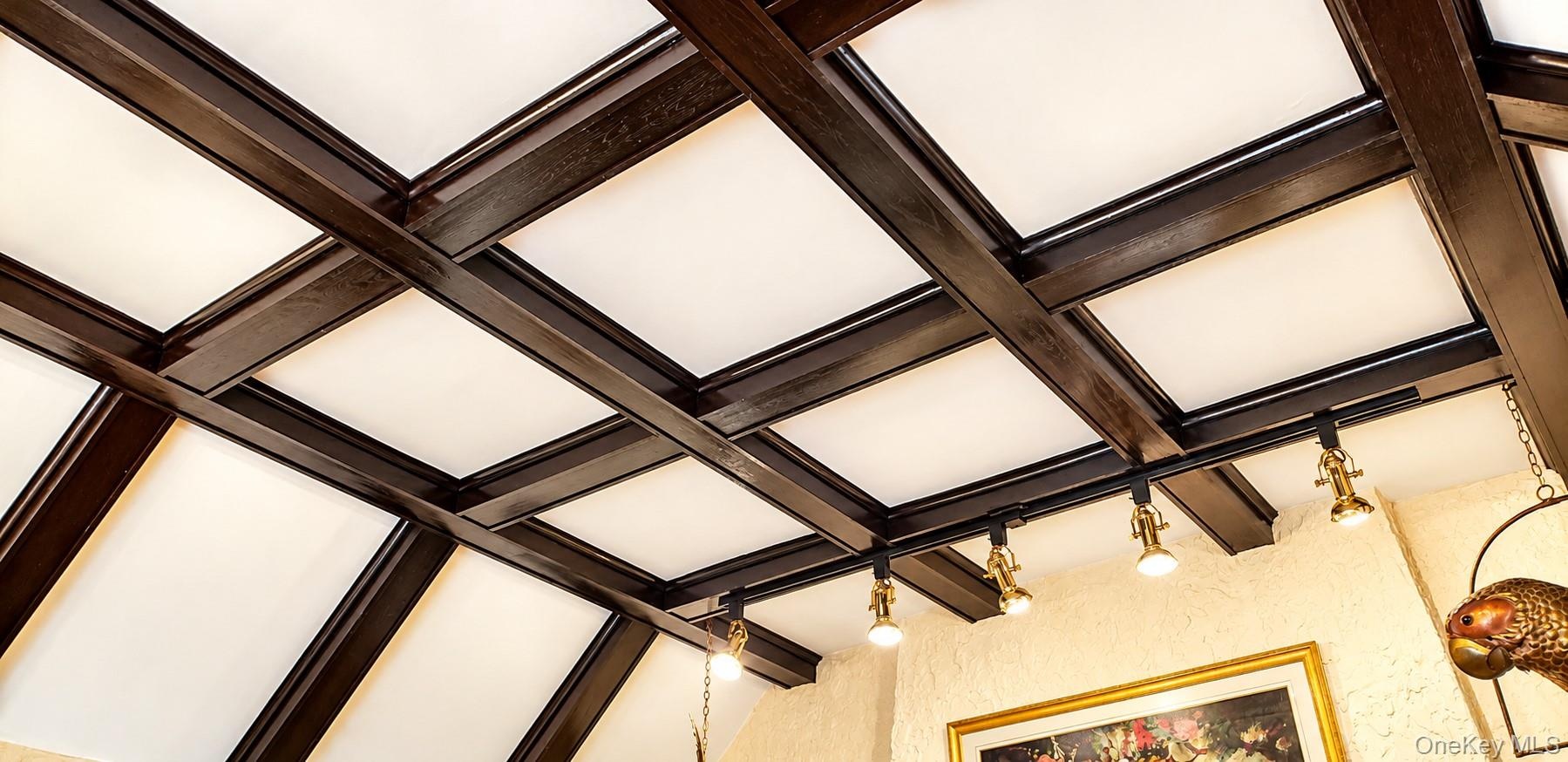 Coffered ceiling featuring dark wood-finish beams and integrated directional track lighting
