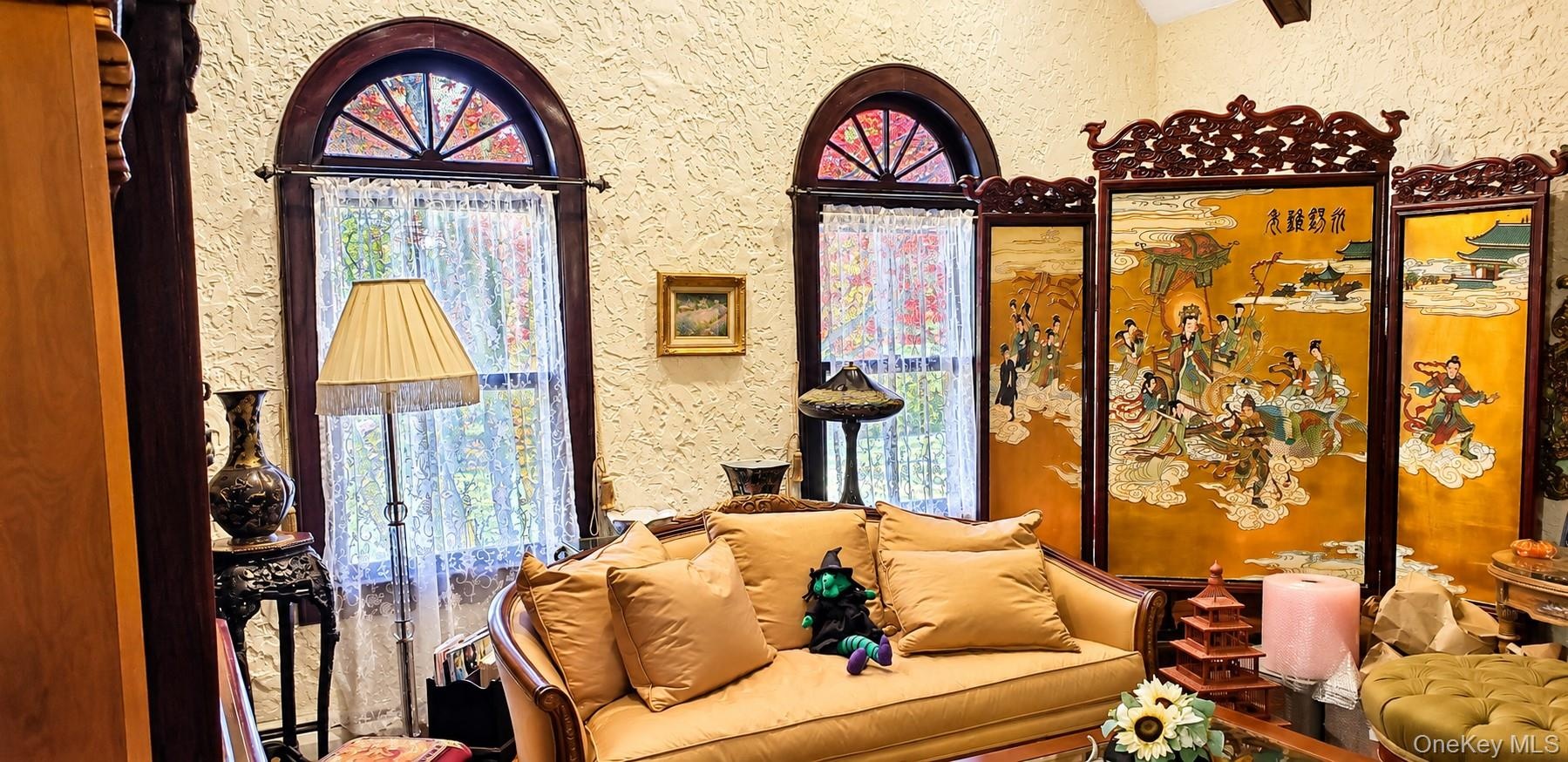 Textured walls, vaulted ceiling, and dual arched windows featuring dark-toned wood trim and semi-circular transom panes