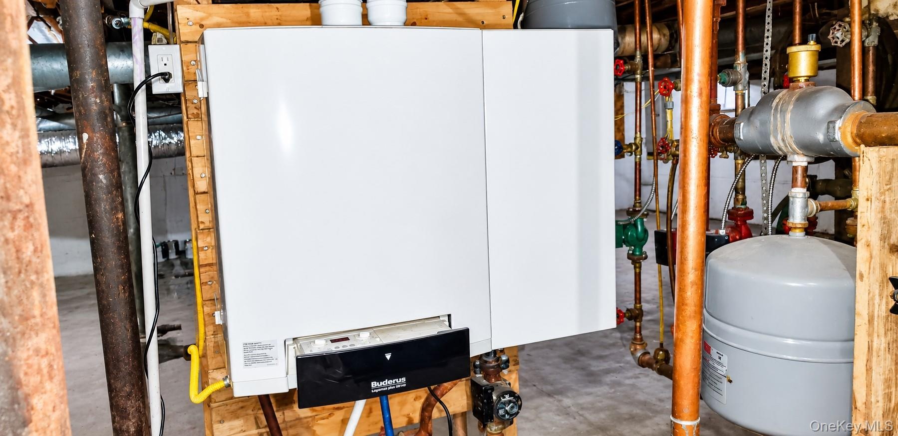 Wall-mounted Buderus heating system featuring copper piping, an expansion tank, and integrated digital controls