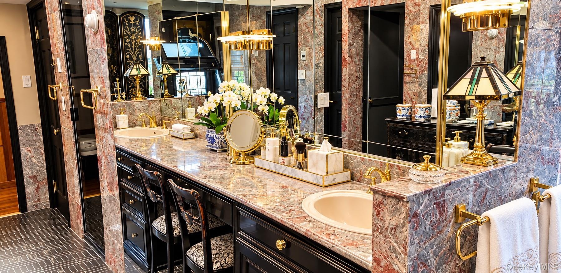 Dual vanity with integrated stone-patterned countertops, undermount sinks, brass-toned hardware, extensive wall mirrors, and black built-in cabinetry