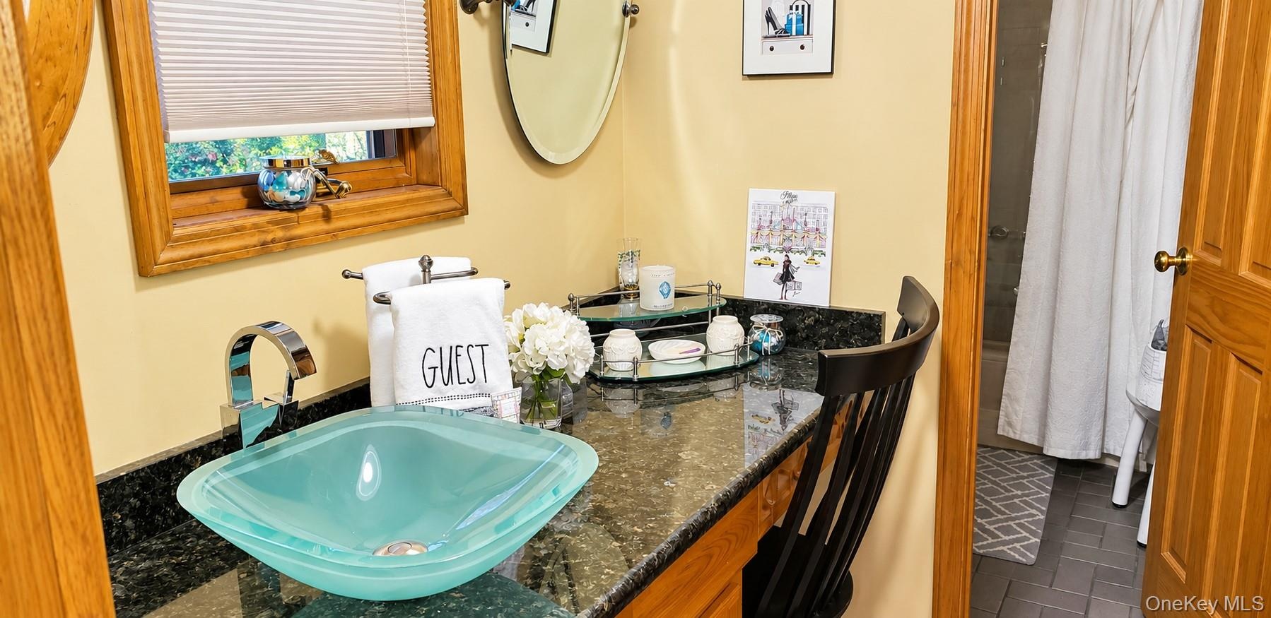 Bathroom vanity featuring a glass vessel sink, dark stone countertop, wood cabinetry, and a chrome faucet