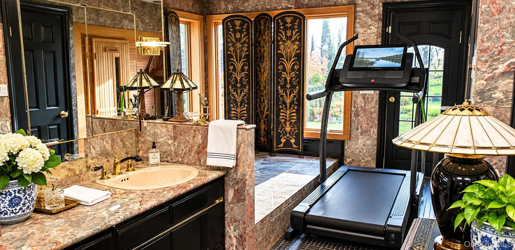 Stone-surfaced vanity with integrated sink, stone wall cladding, built-in wooden cabinetry, multi-paned glass doors, and large wall-mounted mirror