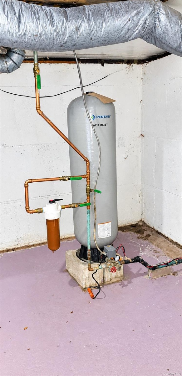 Water pressure tank featuring copper piping, an inline filtration system, and a concrete base