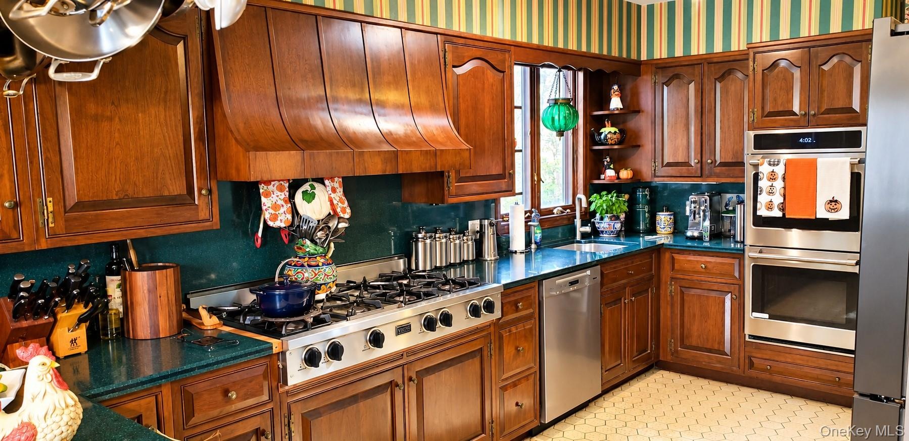 Custom wood cabinetry with an integrated range hood, professional-grade gas cooktop, double wall ovens, stainless steel dishwasher, and solid-surface 