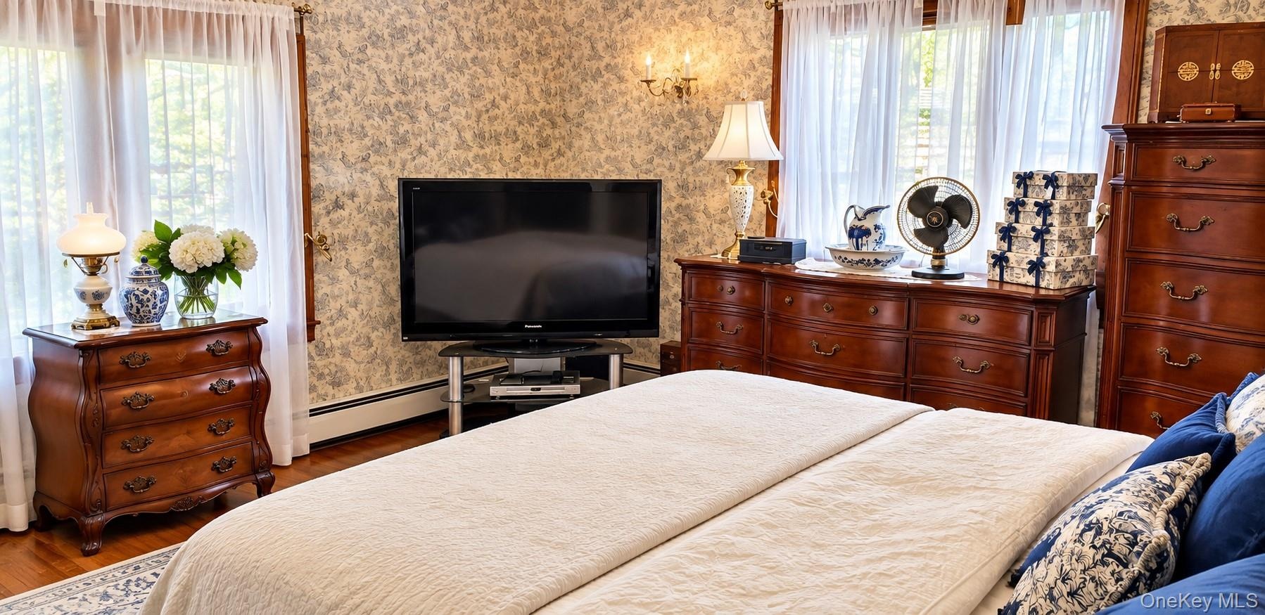 Interior room featuring hardwood flooring, patterned wallcovering, multi-pane windows, and wall-mounted light fixtures