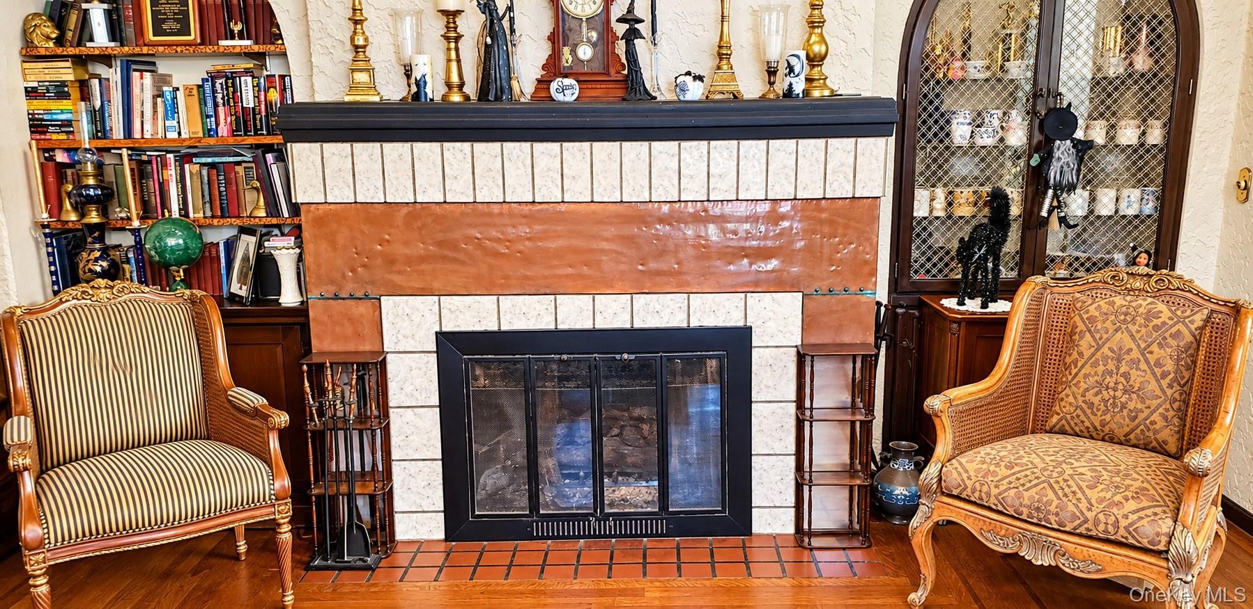 Fireplace featuring decorative dual-tone tile surround, recessed arched display cabinetry, and built-in wood shelving