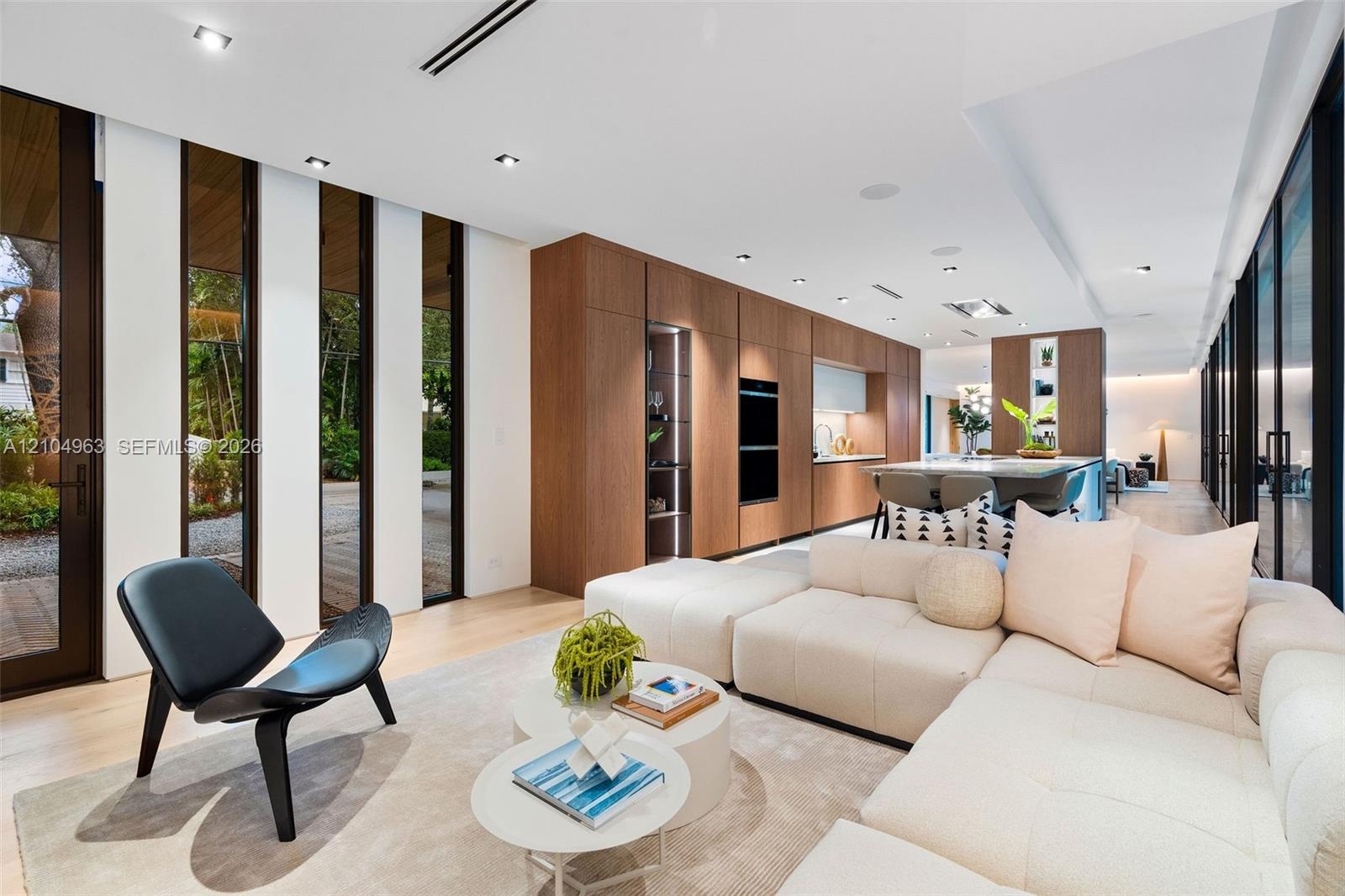Open-concept space featuring wood-finish flooring, floor-to-ceiling windows, recessed lighting, and full-height wood cabinetry with built-in wall oven