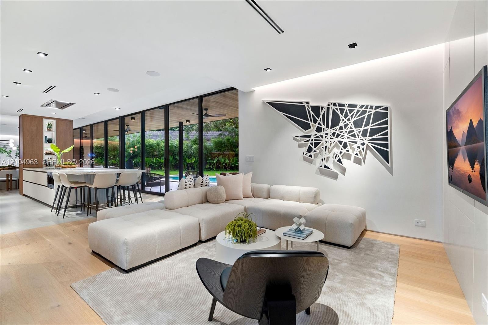 Open-concept floor plan featuring expansive floor-to-ceiling glass panel walls, wood-finish flooring, recessed lighting, and a modern kitchen island w
