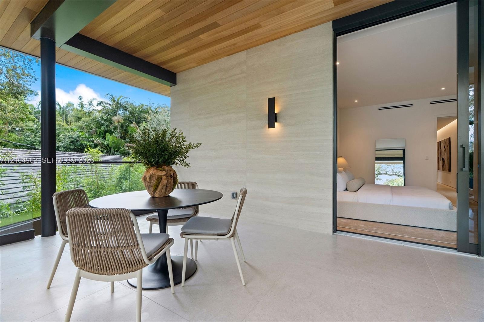 Covered balcony featuring wood-paneled ceiling, stone-finish wall cladding, large-format tile flooring, frameless glass railings, and expansive slidin