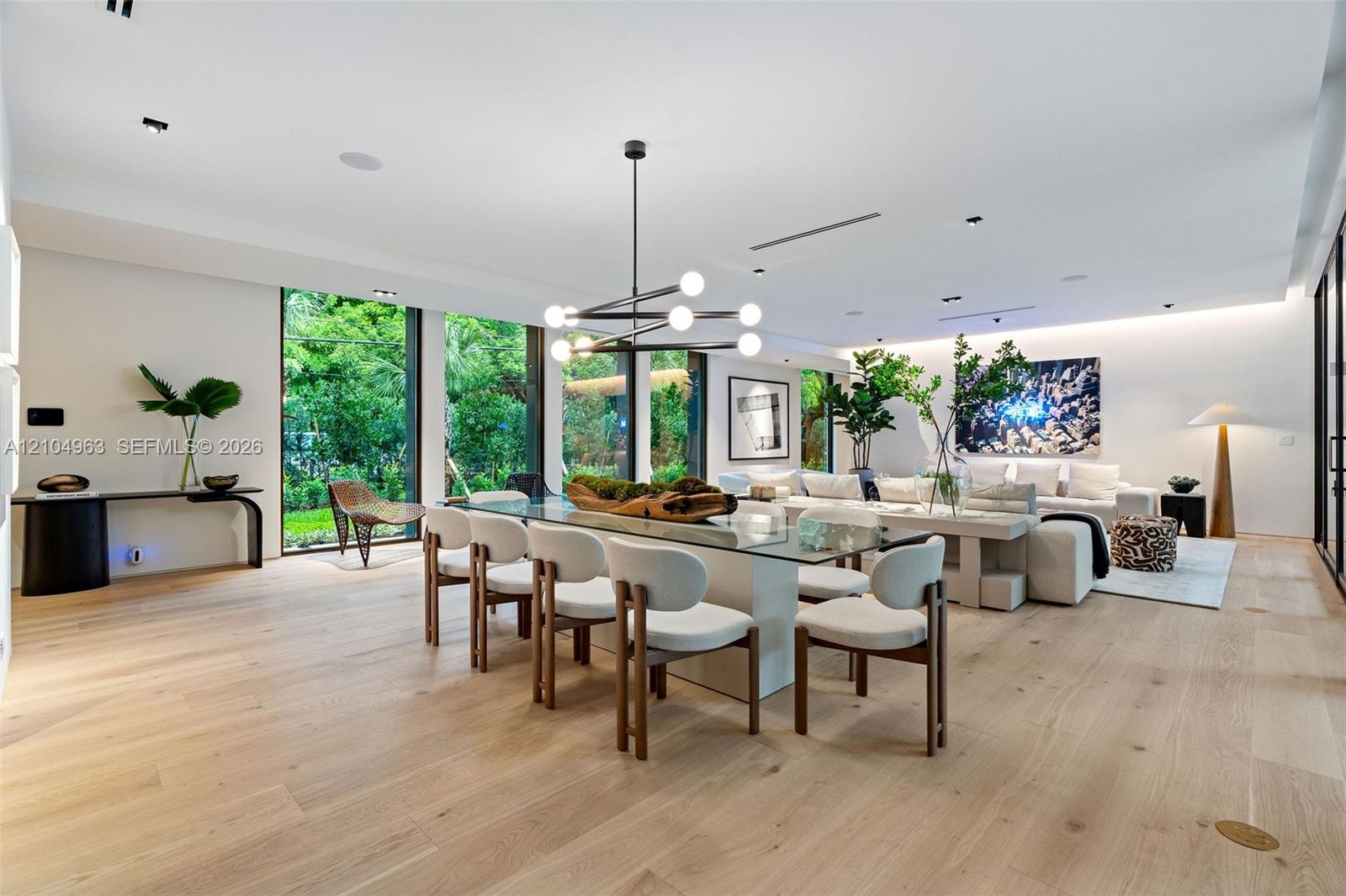 Open-concept living space featuring wood-finish flooring, floor-to-ceiling windows, recessed lighting, and a modern tiered geometric chandelier