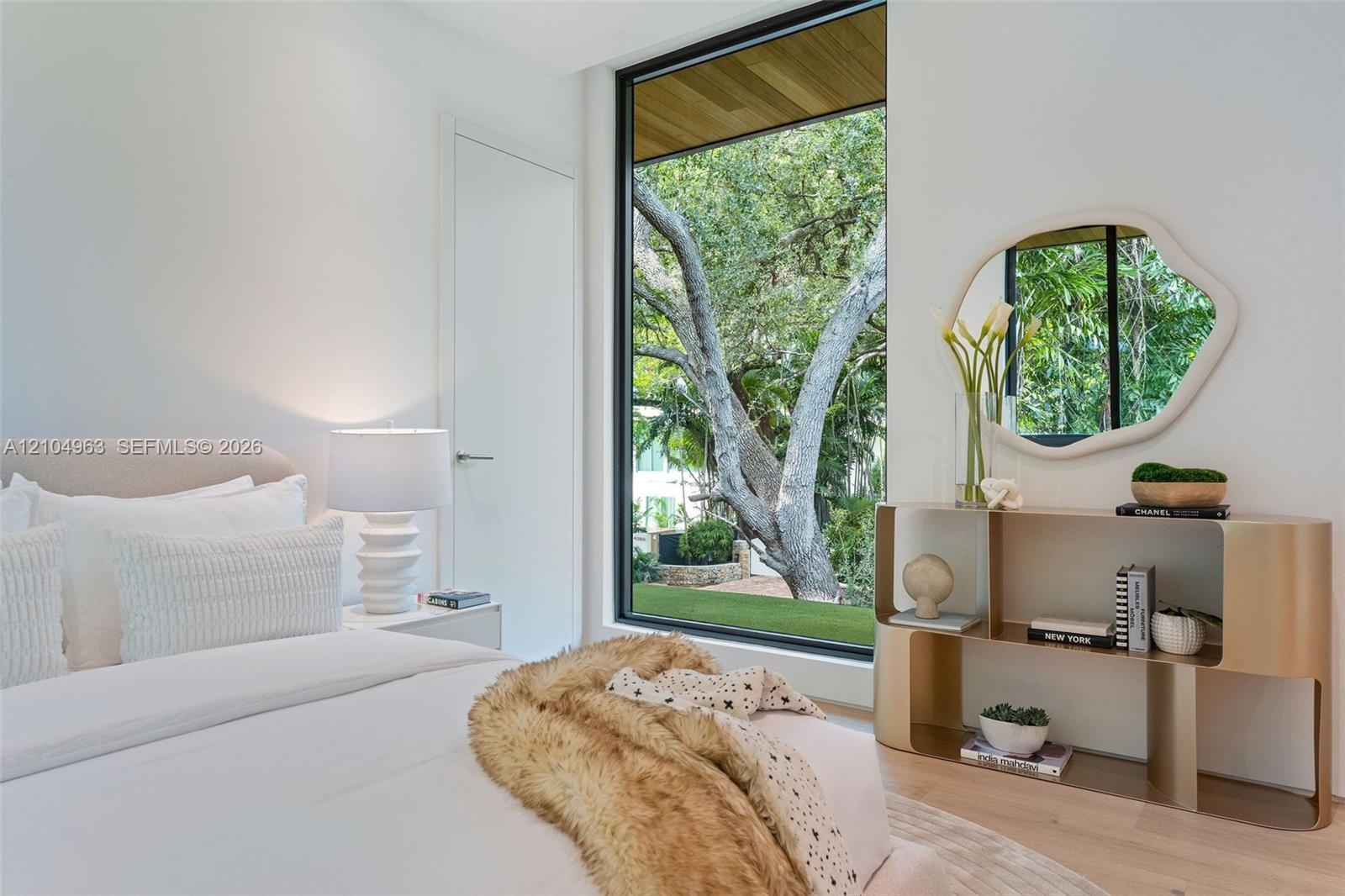 Floor-to-ceiling fixed window, wood-paneled ceiling accent, light-toned wood-finish flooring, and crisp white wall finishes