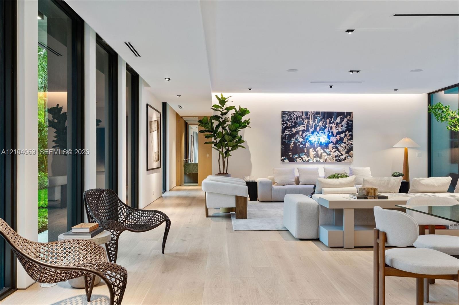 Wide-plank wood-finish flooring, floor-to-ceiling glass panels, recessed architectural lighting, and cove ceiling accent lighting