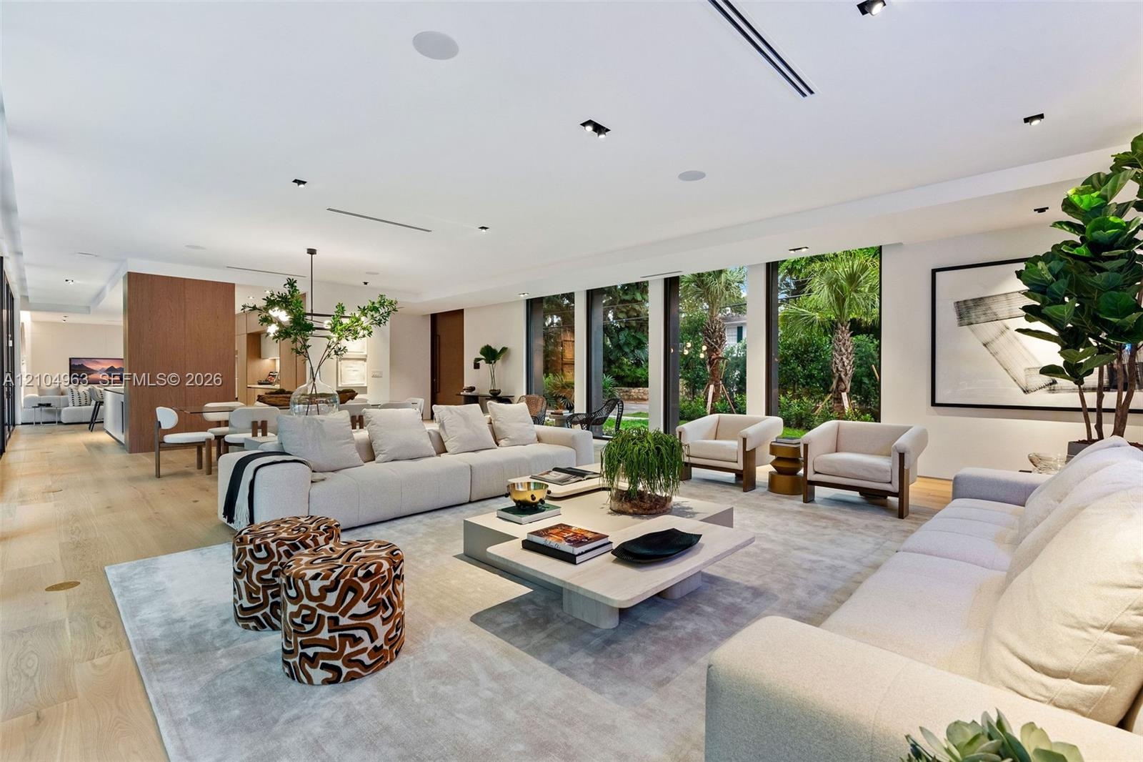 Open-concept living space featuring wood-finish flooring, floor-to-ceiling glass paneling, recessed ceiling lighting, and built-in audio speakers