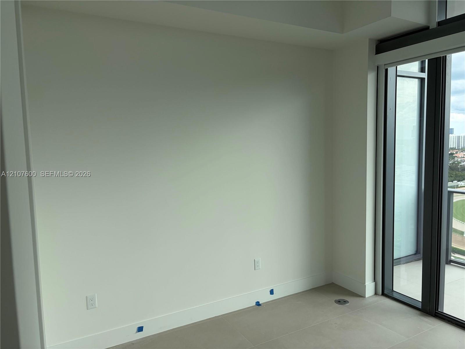 Neutral-toned tile flooring, floor-to-ceiling glass paneling, and an exterior balcony door
