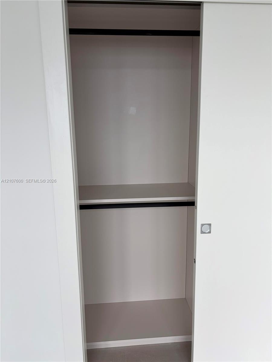 Sliding closet doors featuring a white finish, horizontal shelving, built-in rods, and a square metal handle